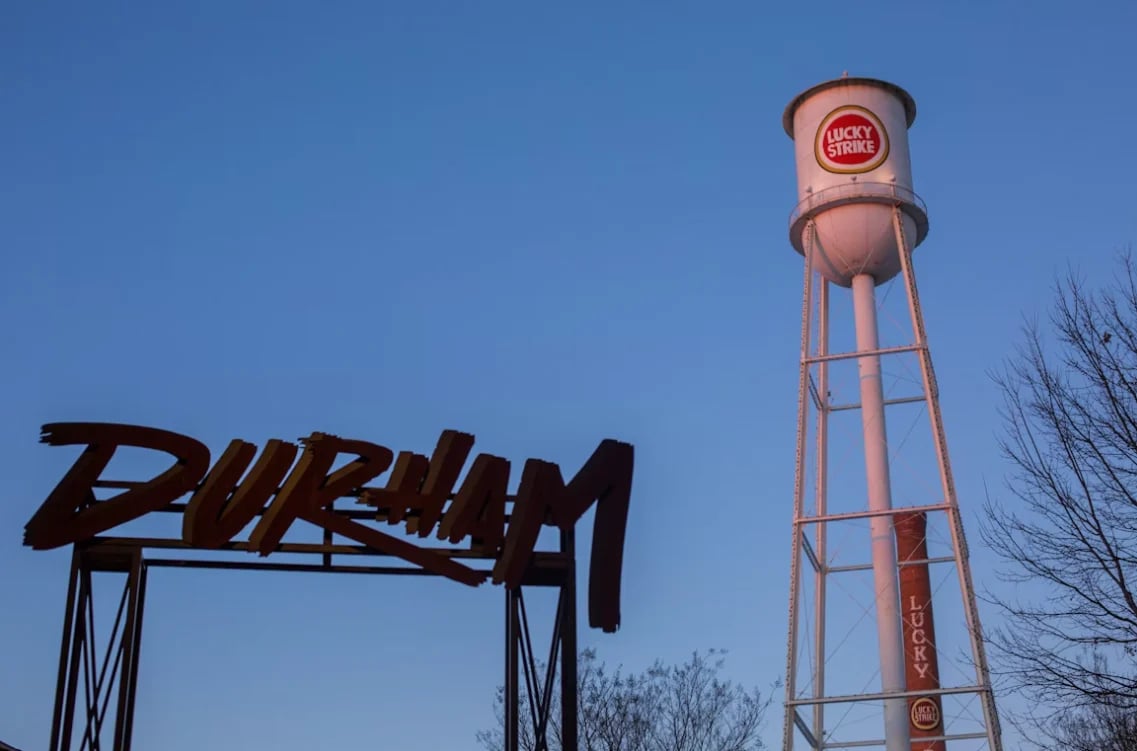 Vintage Burlap sign and red water tower against blue sky with bare tree branches