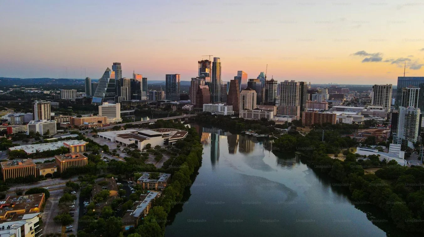 Aerial view of Austin skyline at sunset with Lady Bird Lake and downtown buildings reflecting in water