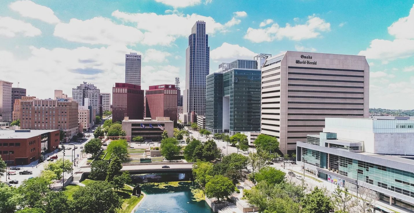 Aerial view of downtown Austin skyline with tall buildings, green spaces, and a river running through the urban landscape