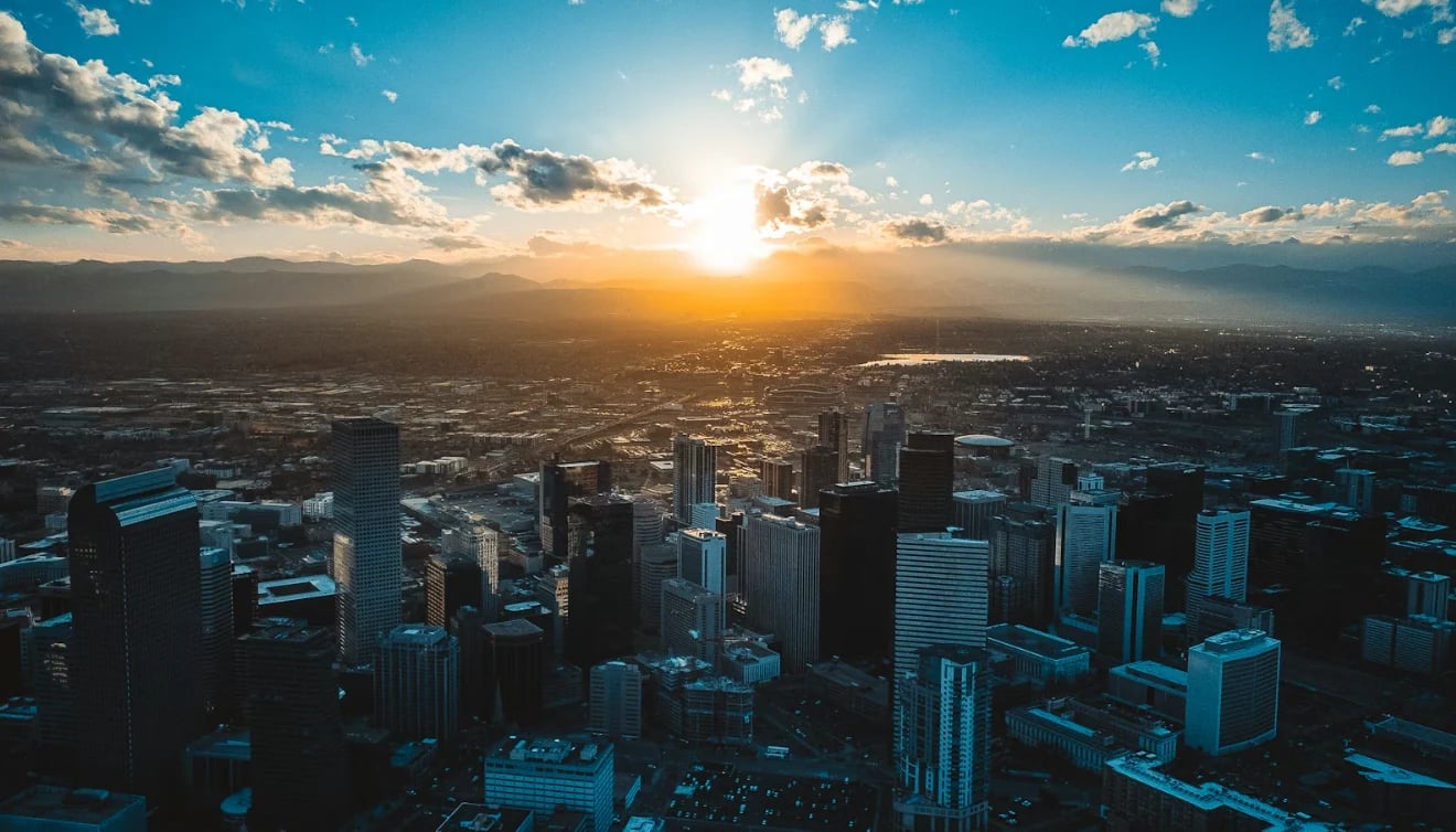 Aerial cityscape at sunset with downtown skyscrapers silhouetted against golden sky and clouds