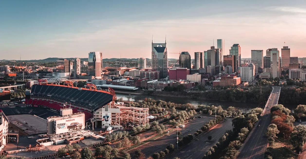 Aerial view of Nashville skyline at sunset with football stadium and green hillside in foreground